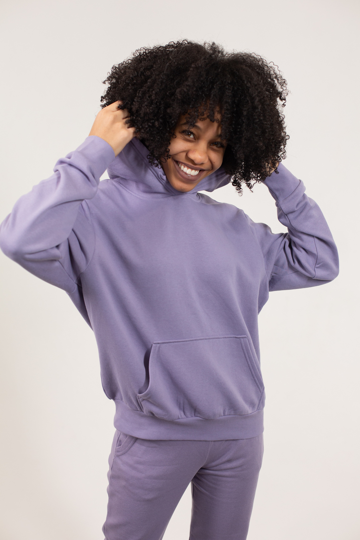 Cheerful black woman putting on hood of sweatshirt